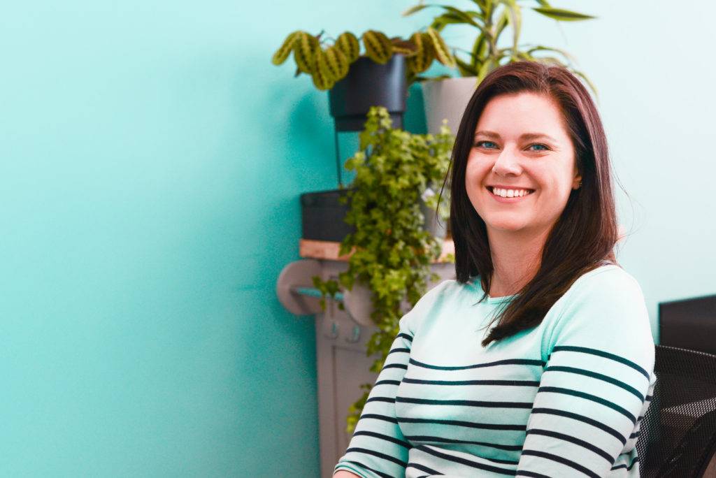 A woman sitting in an office chair smiling at the camera